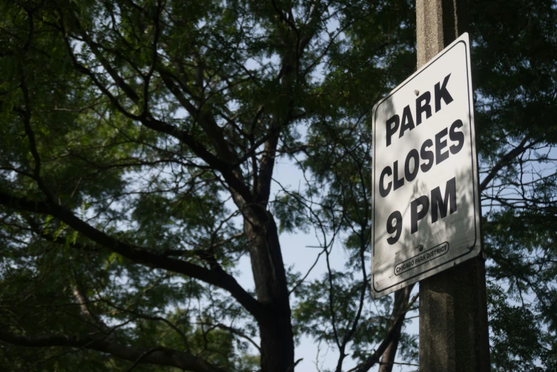 a sign reading mark closes 9 pm near a tree