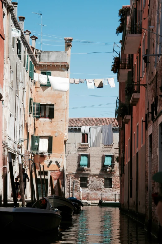 a narrow canal with parked boats and buildings on both sides