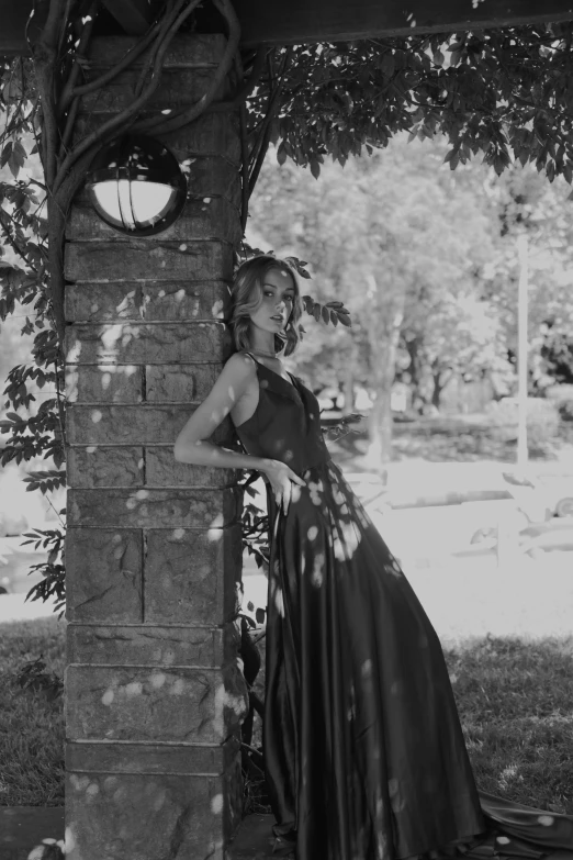 woman in dress leaning against wall outdoors