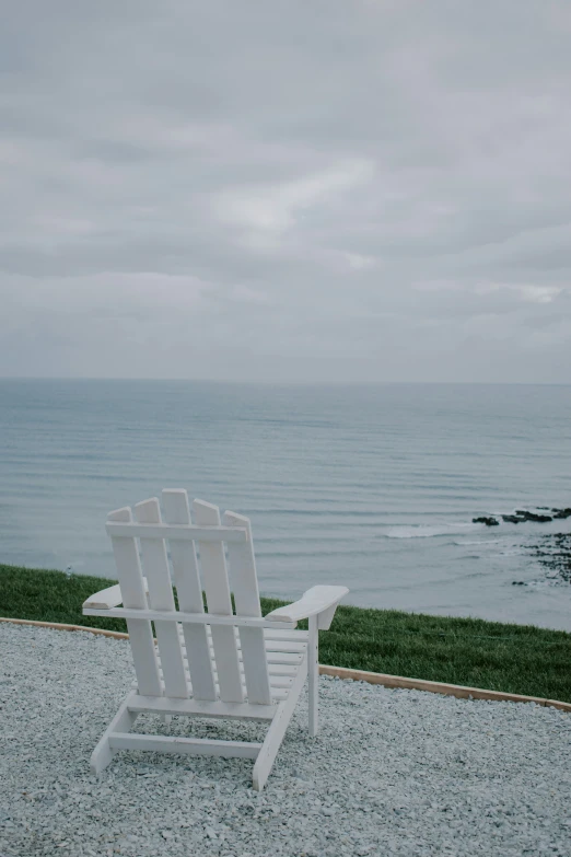 a white chair in the sand by the ocean