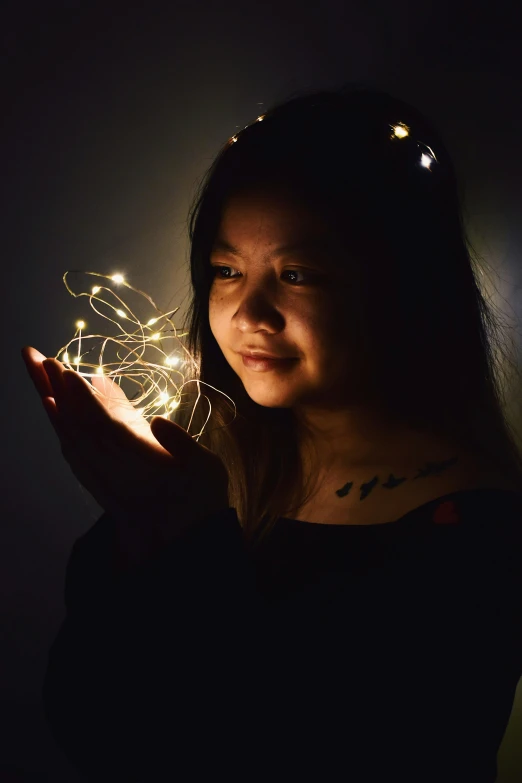 an asian woman holding out her hand with a sparkle
