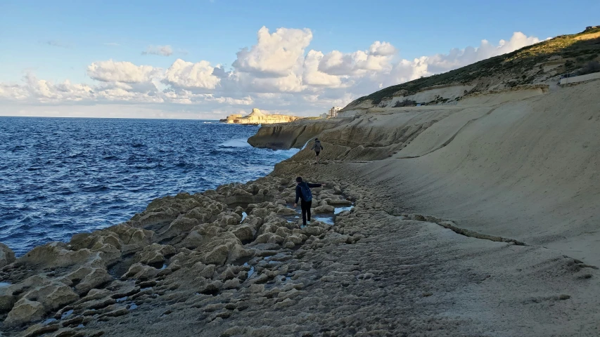 a man walking on a rocky beach next to the ocean