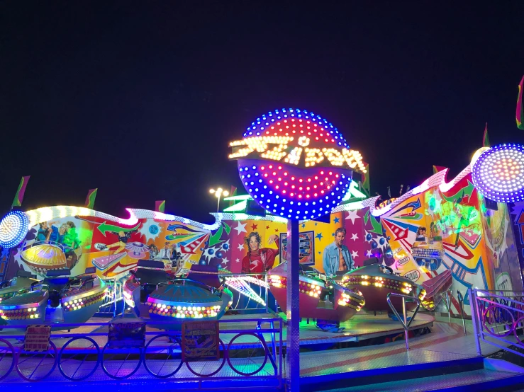 a number of carnival rides in a large crowd at night