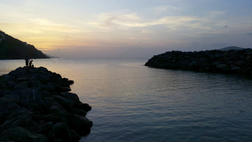 two people standing on a pier looking out at the water