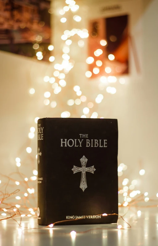 a bible is sitting in front of some christmas lights