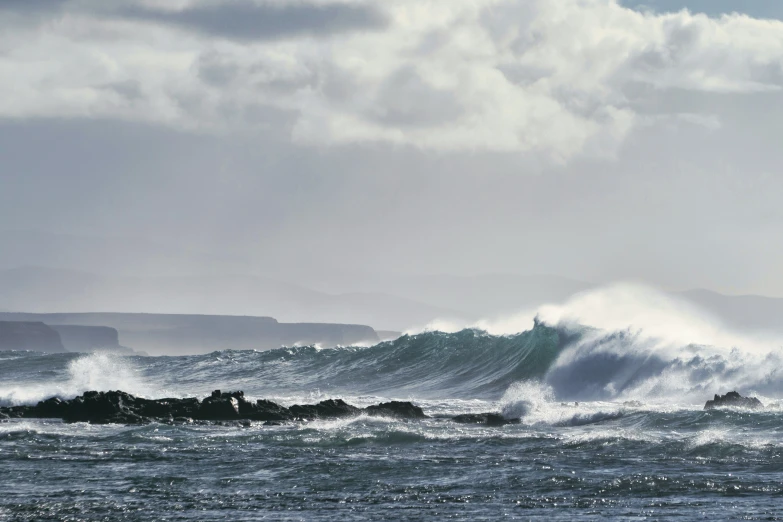 a very big wave in the ocean by some rocks