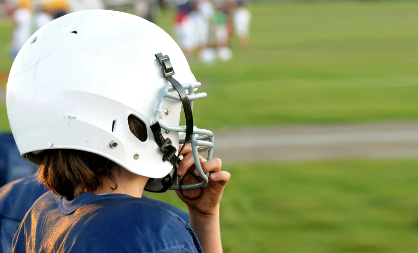 a close up of a person with a helmet on holding soing to their ear