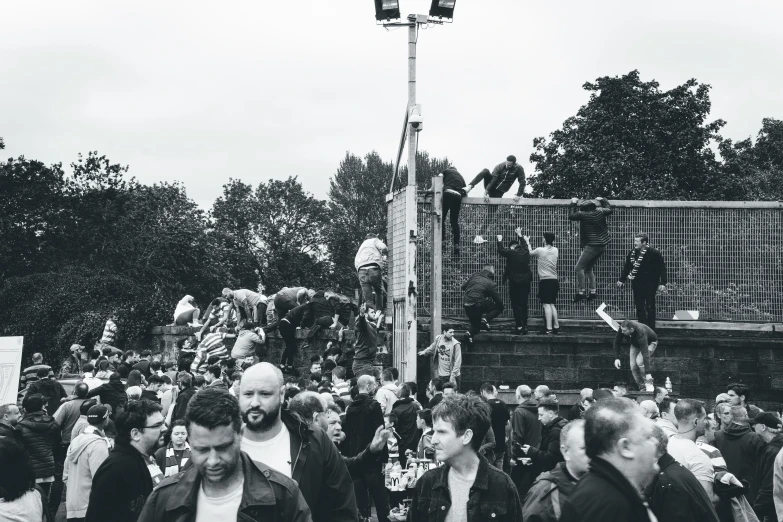 a large group of people gathered together near some fence