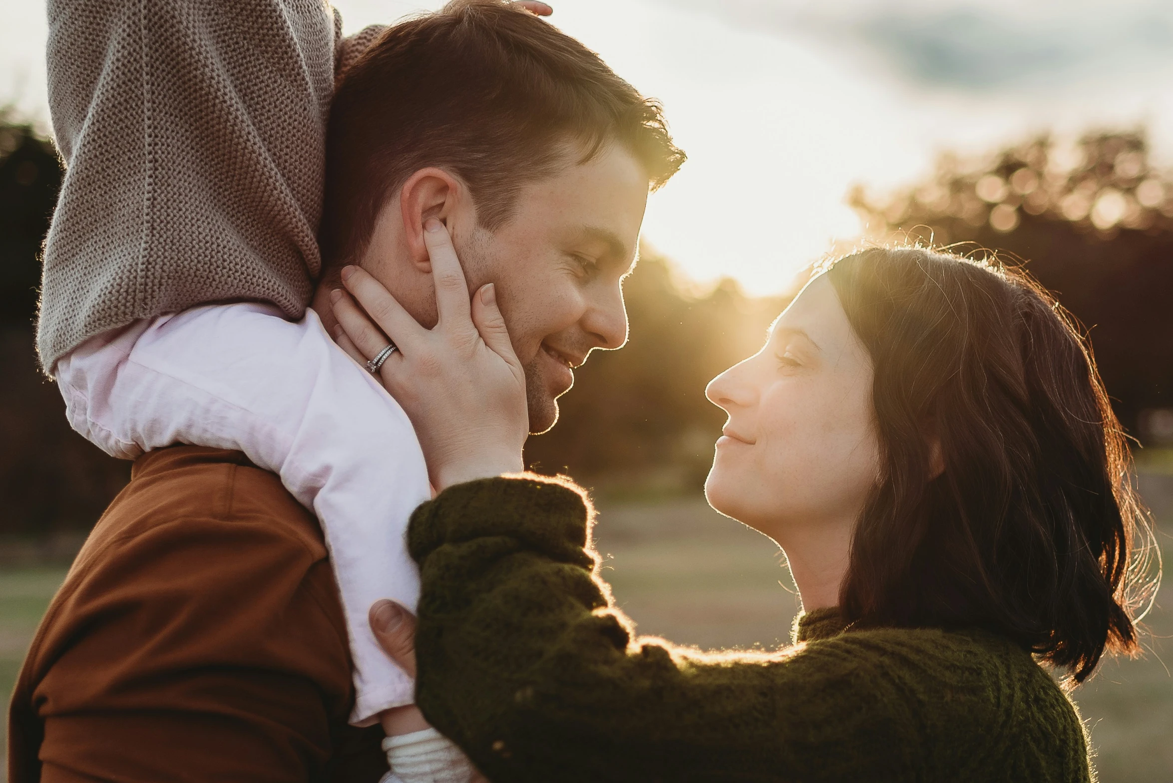 a young man and woman have their faces close to each other and a girl's hand is resting on her shoulders