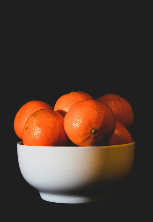 this is a white bowl full of oranges