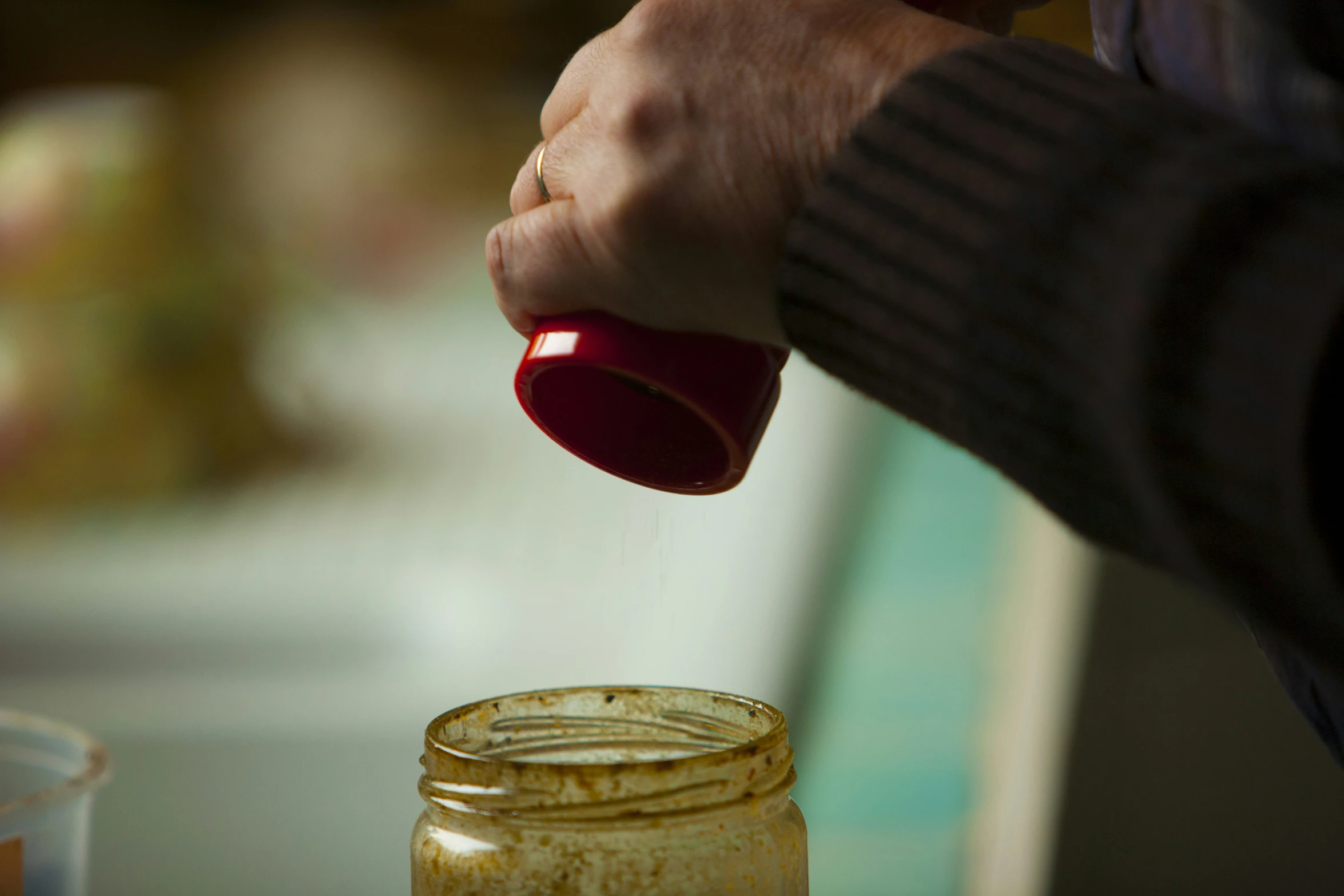 a person pouring soing into a glass jar