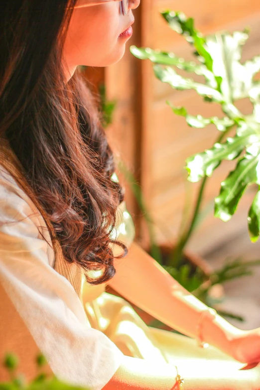 a girl with long hair holding onto a plant