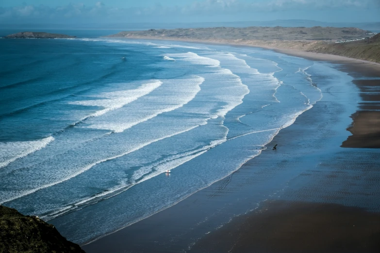 a man that is walking on the side of a beach