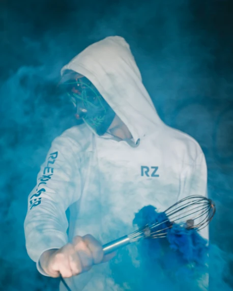 a man is in the smoke holding a blue whisk