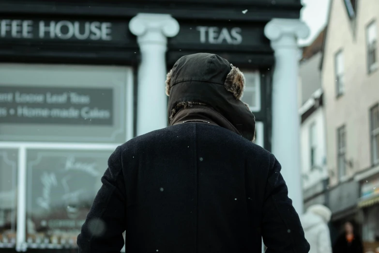 the man is walking in front of the cafe