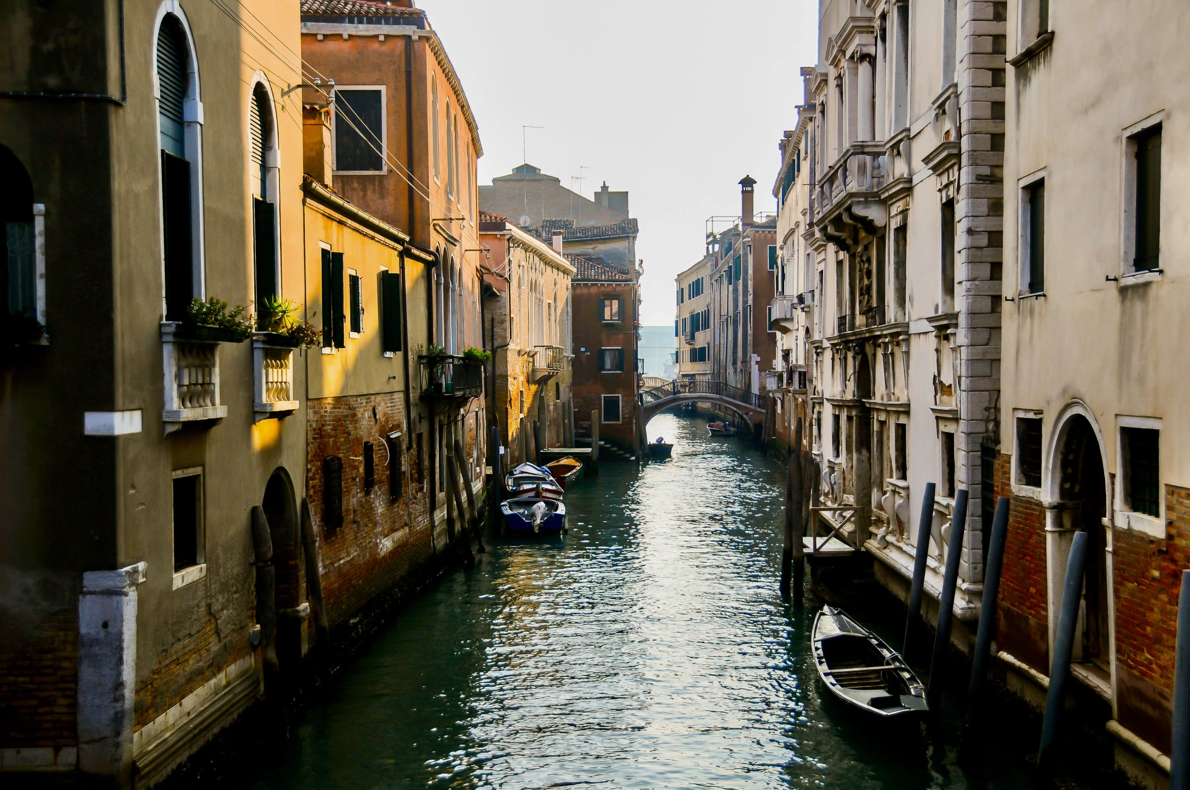 boats floating down the middle of a narrow canal