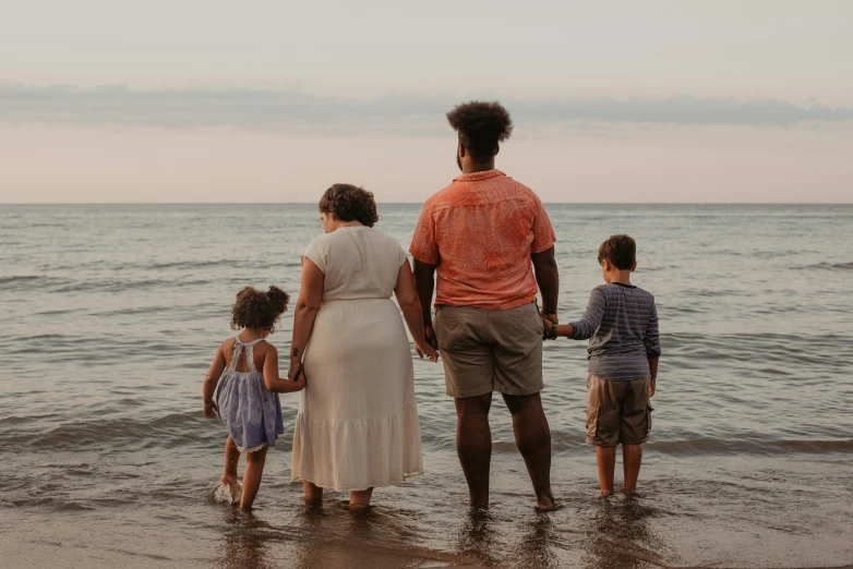 a family stands on the beach with two children