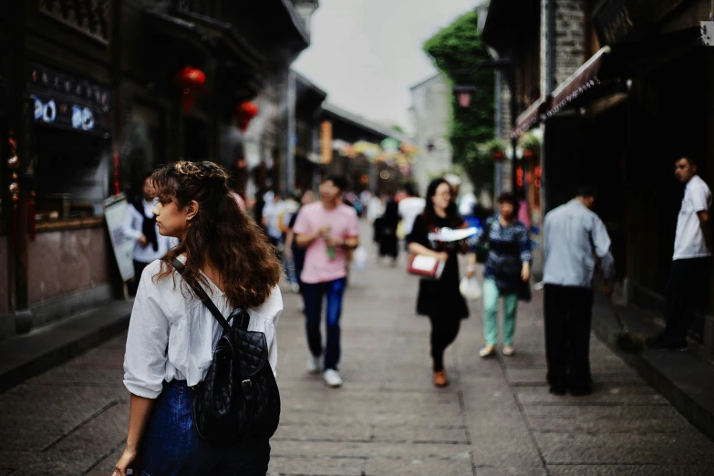 a woman walks down a busy street as people walk past