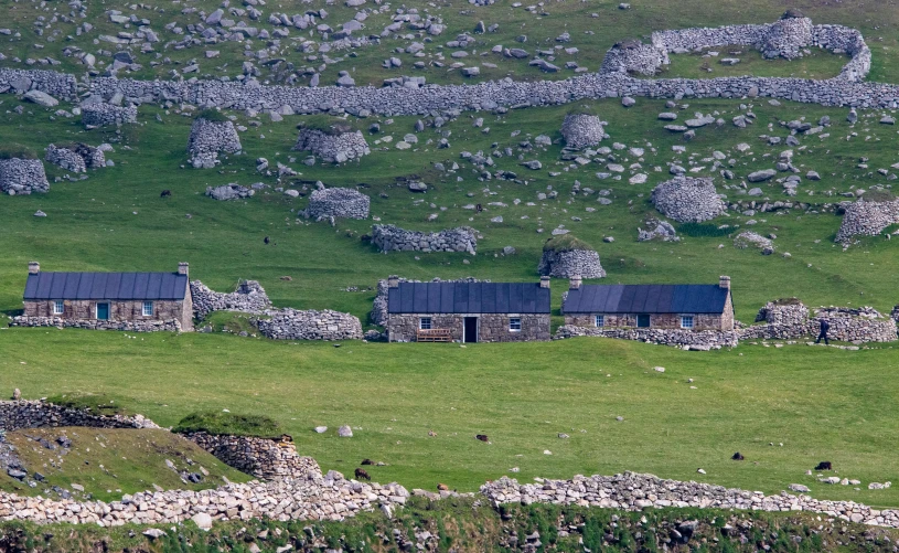 two stone houses sitting on a hillside surrounded by rocks