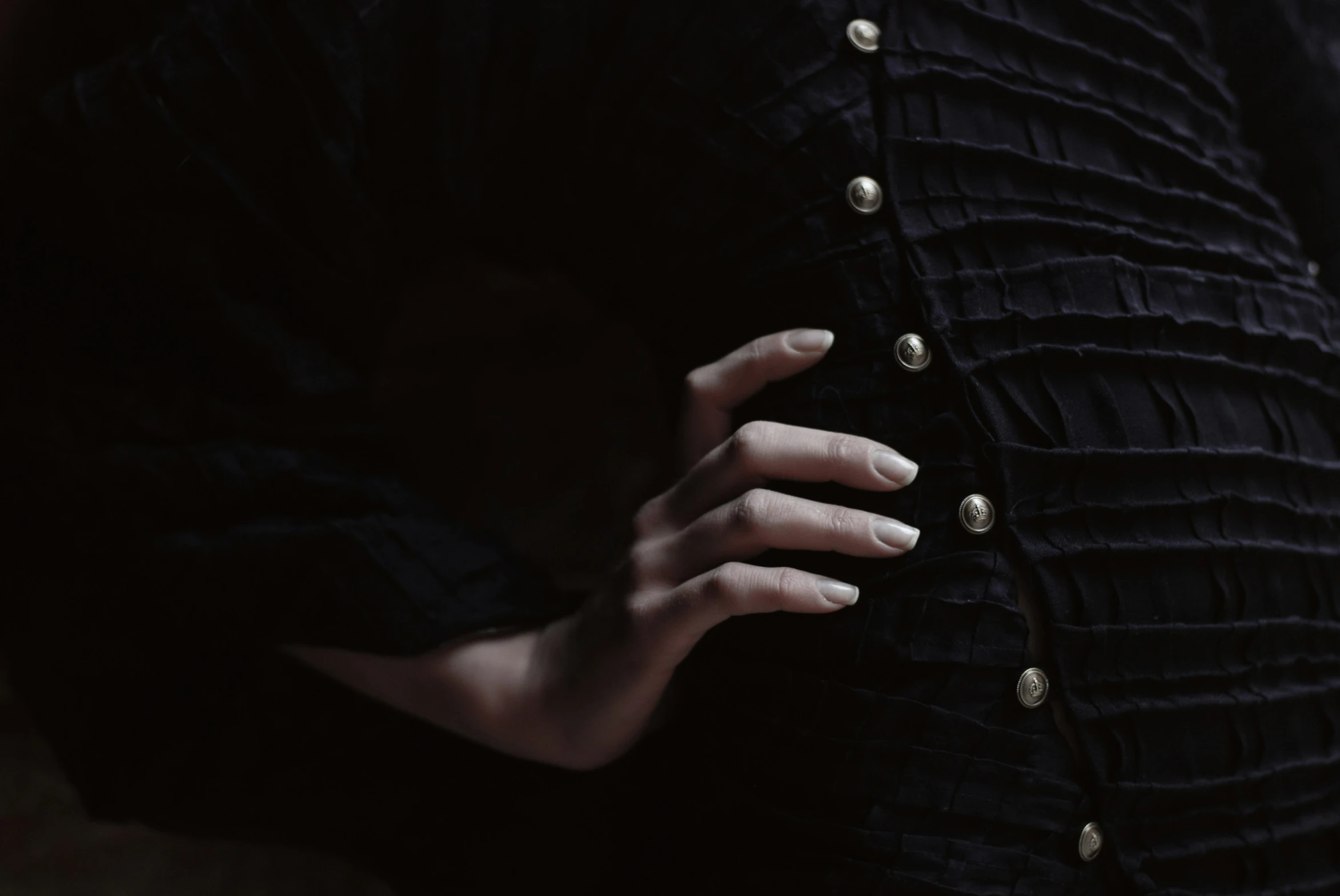 a person's hands are on the edge of a black dress