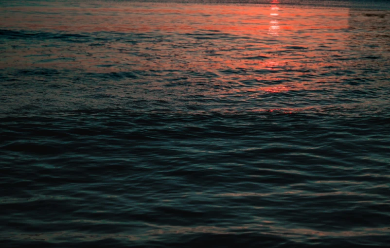the sun is setting over a calm ocean