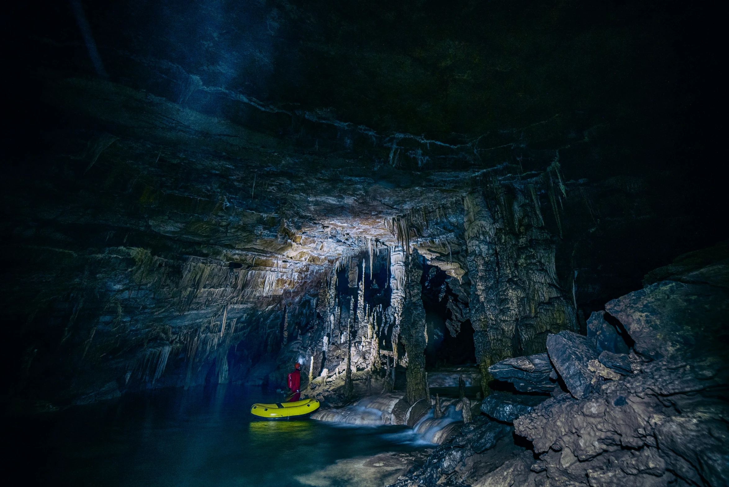 a yellow kayaker in a dark cave with black walls