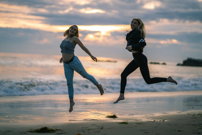 two women jumping in the air on the beach