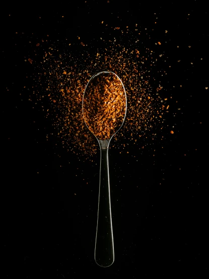 an orange substance is spilling over a black spoon