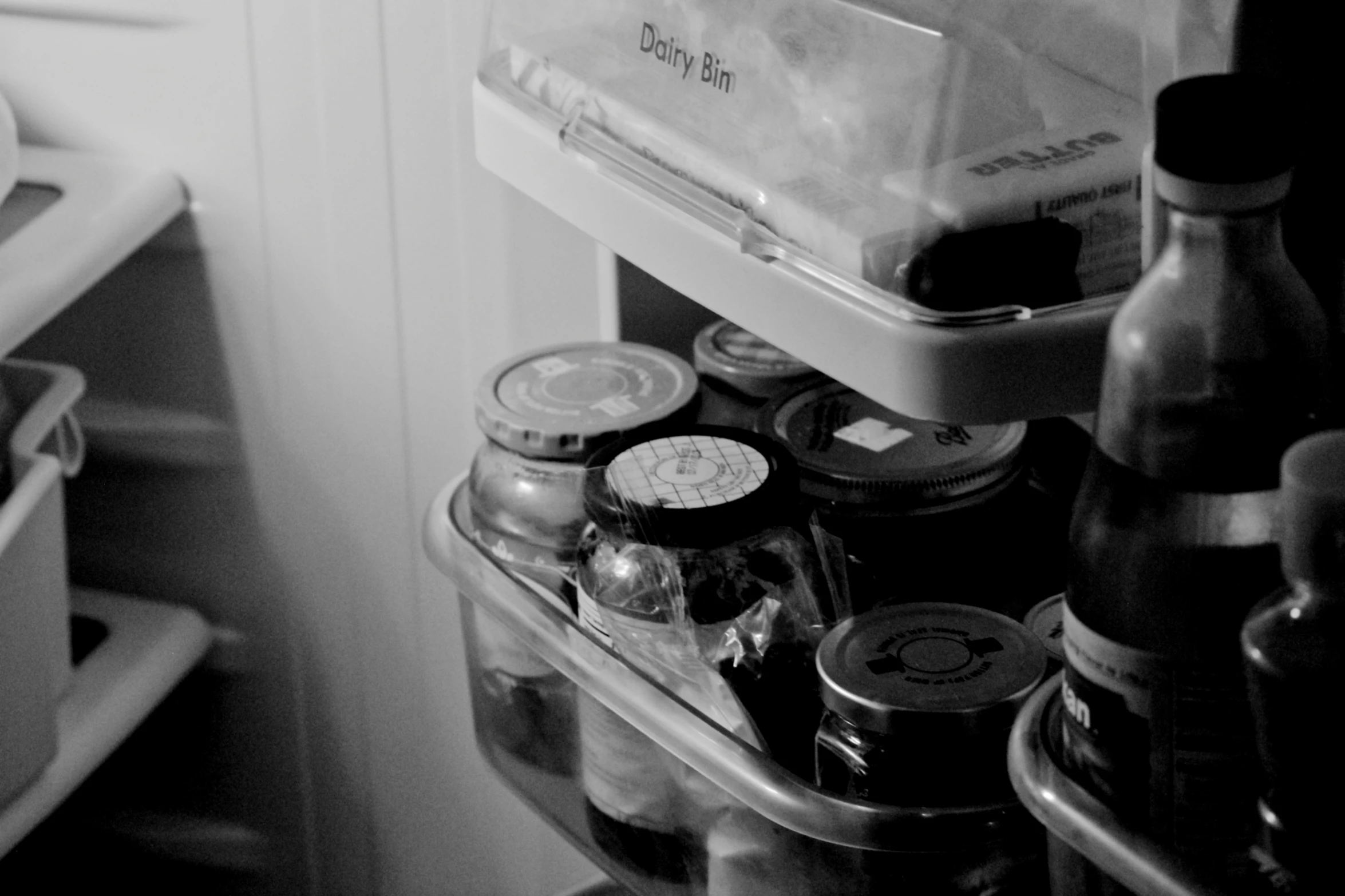 an open refrigerator has beer and soda cans on the shelf