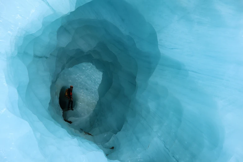 a man is standing in an ice cave with water and ice behind him