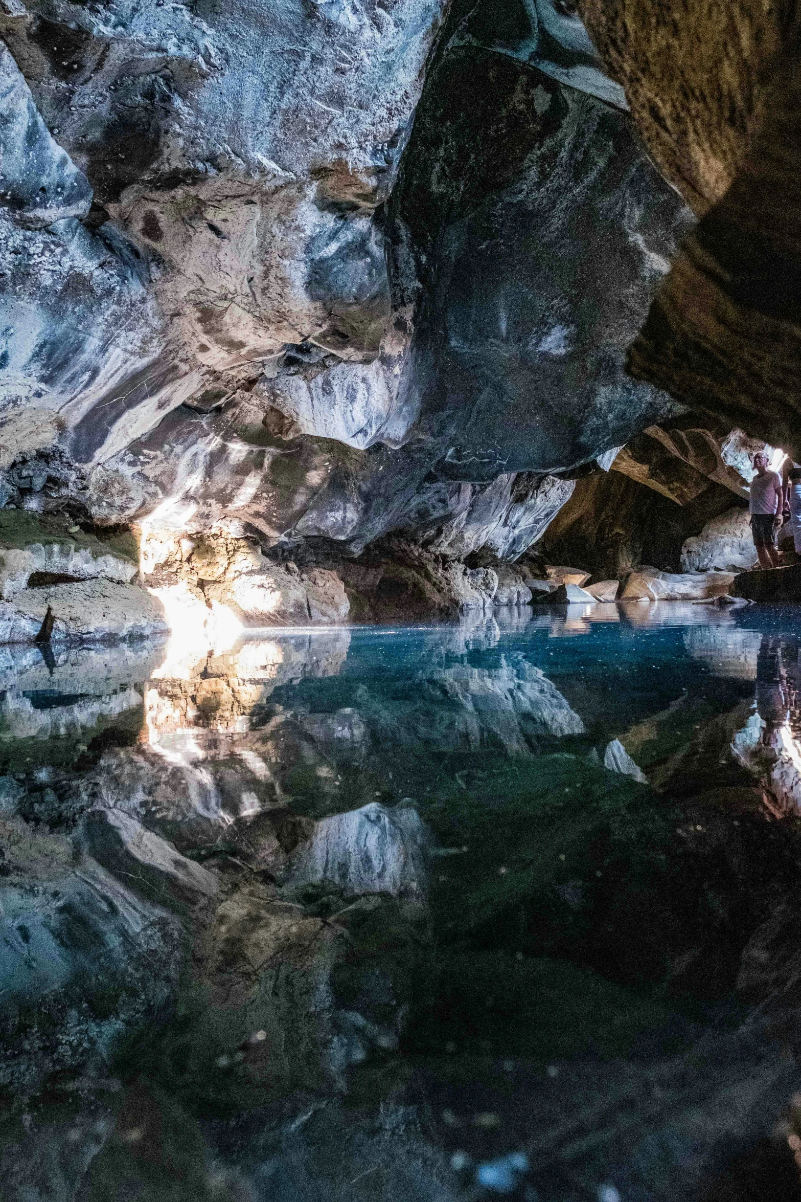 a group of people hanging out by the water at the cave