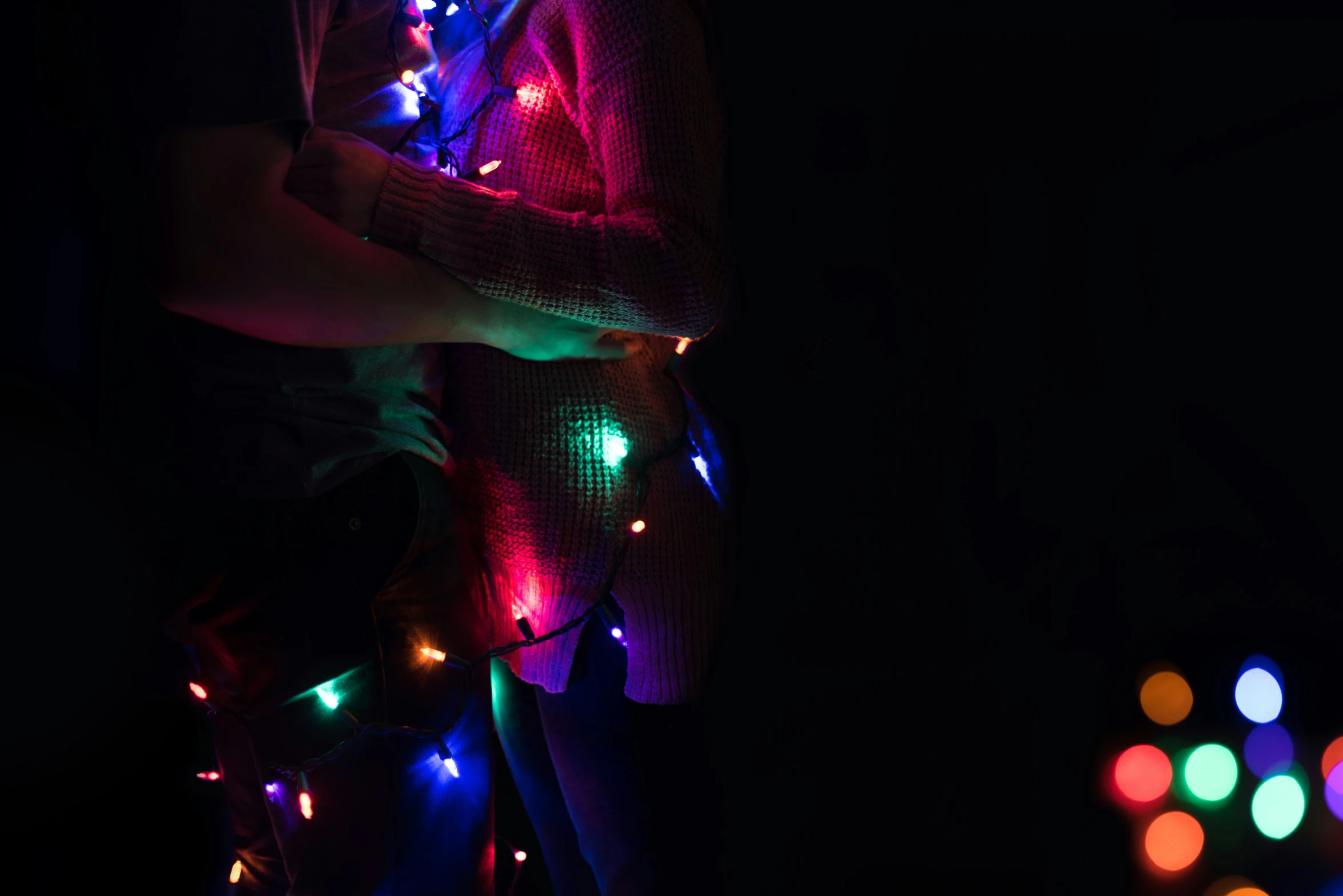 two people hug with a variety of colored lights on them