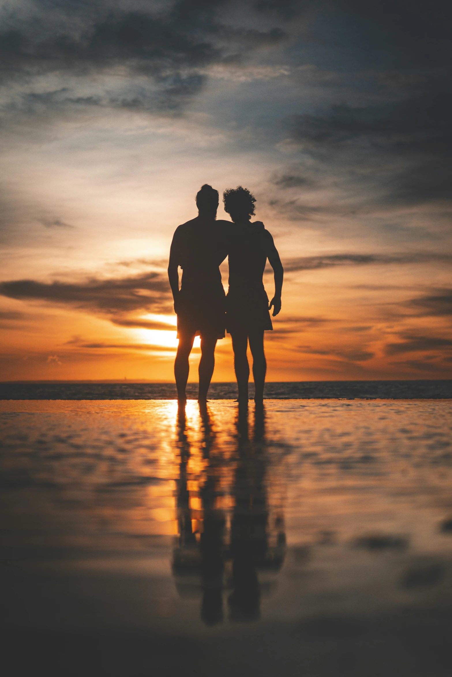 two people standing on the sand at the beach