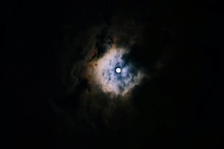 the moon shining in the dark sky with clouds