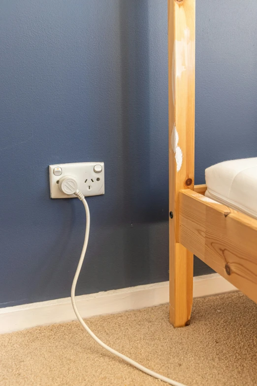 there is a wall socket with an outlet on the side of the bed