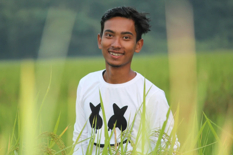 man smiling as he sits in tall grass