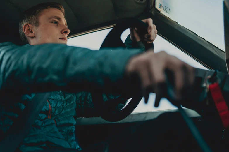 a young man in a car sitting on the driver's seat