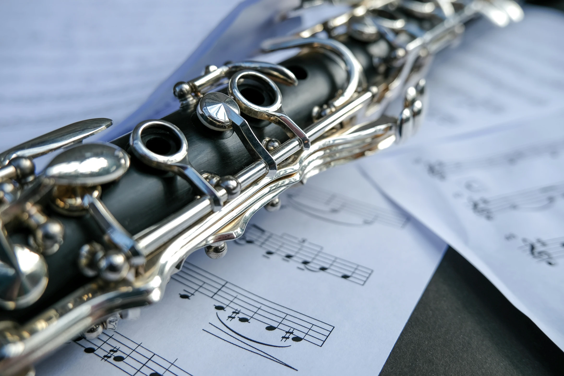 silver flute resting on music sheets with notes