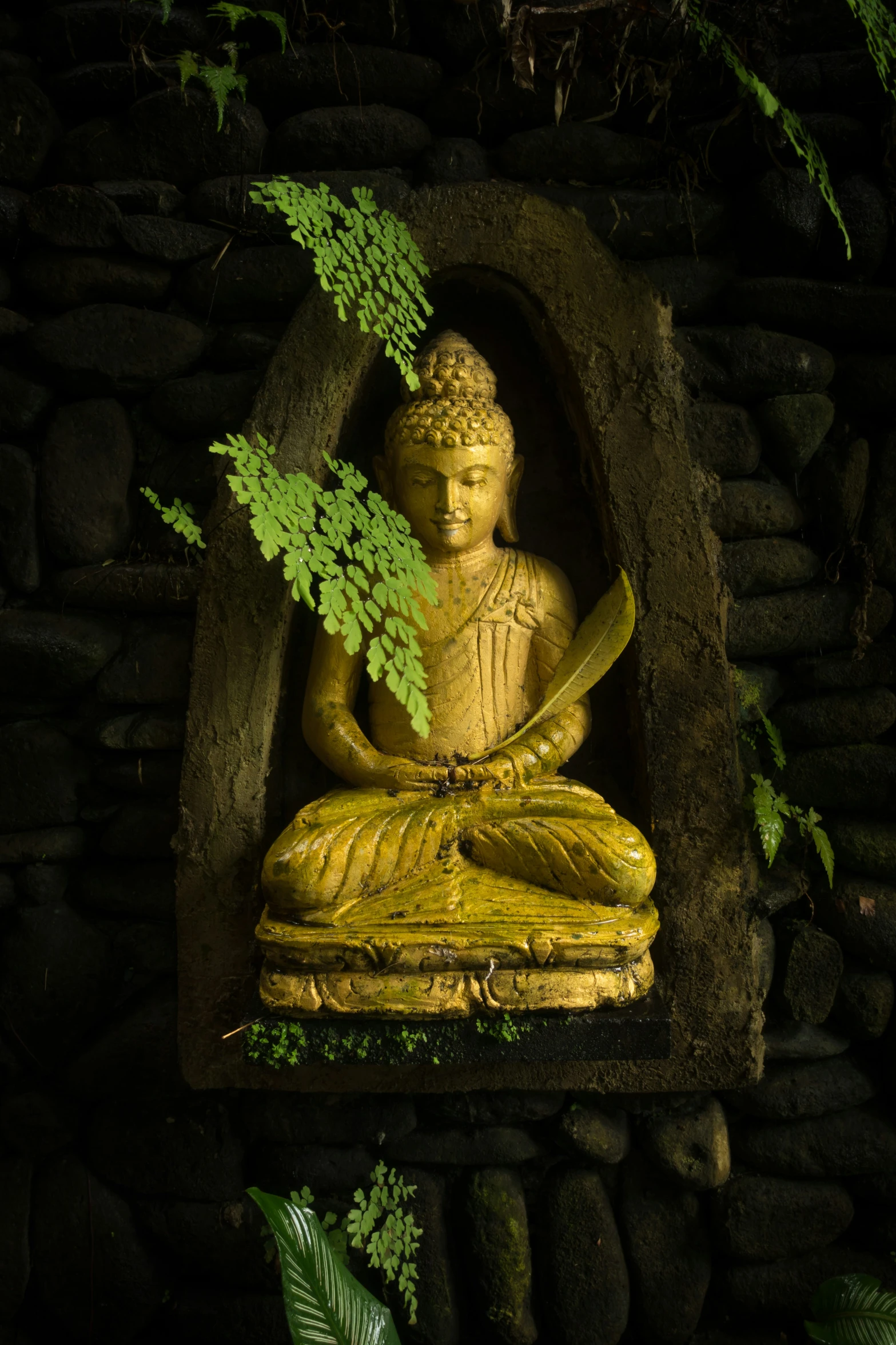 the buddha is made from stones and sits in a hole