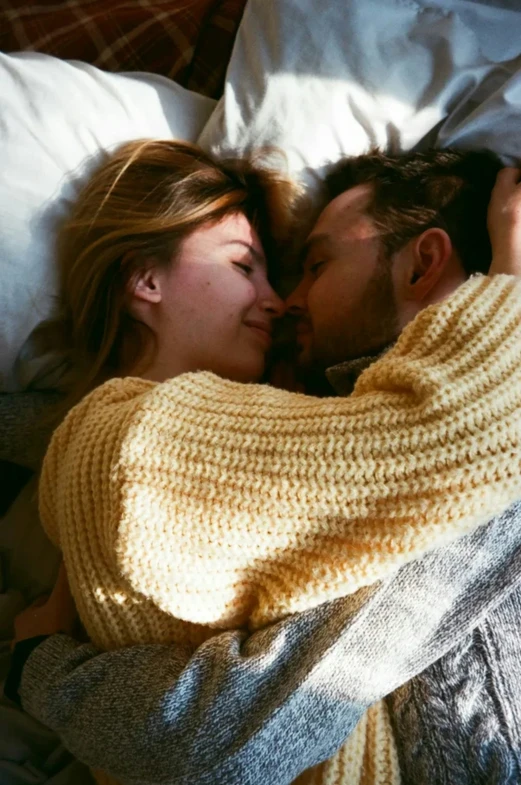 couple wrapped in blankets cuddling under the blanket on bed