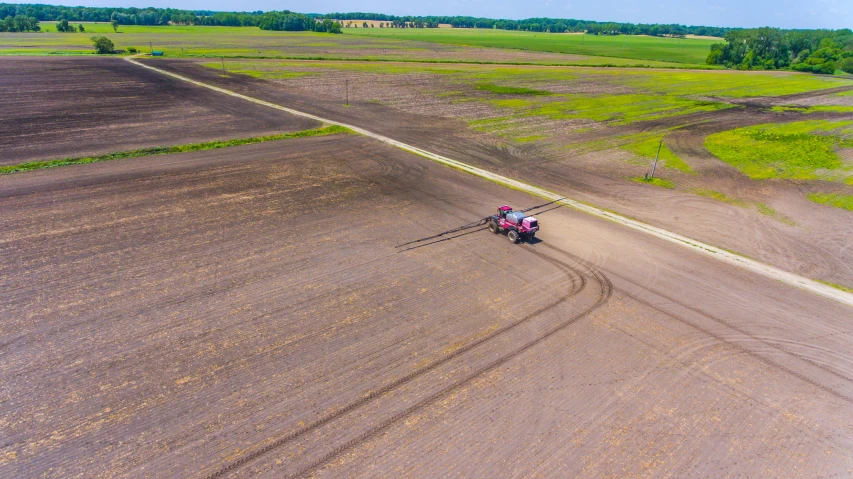 a pink tractor driving in a large field