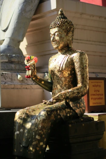 a statue with flowers sits outside near a building
