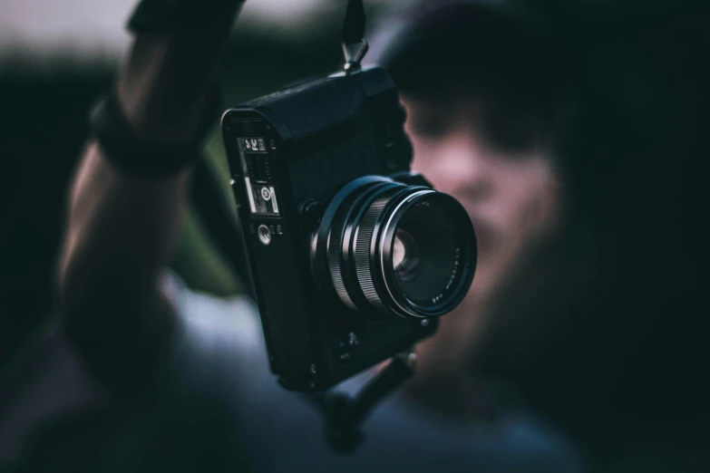 a person holding up a camera with the lens facing the viewer