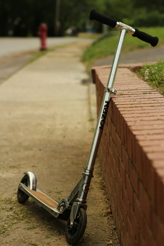 a scooter leaning against the side of a brick wall