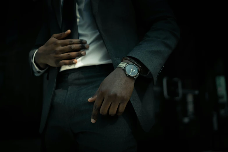 the man with his hand on the wrist of his suit coat