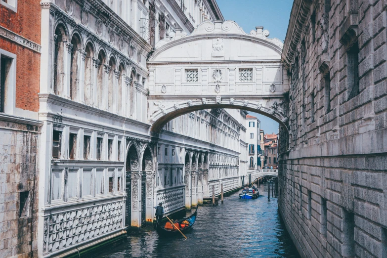 a waterway has arched stone archways and buildings along the sides