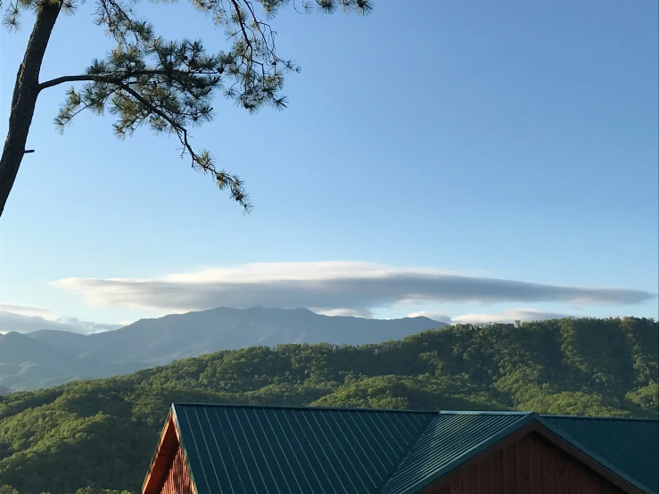 the mountain side view of a cabin with the treeline in front