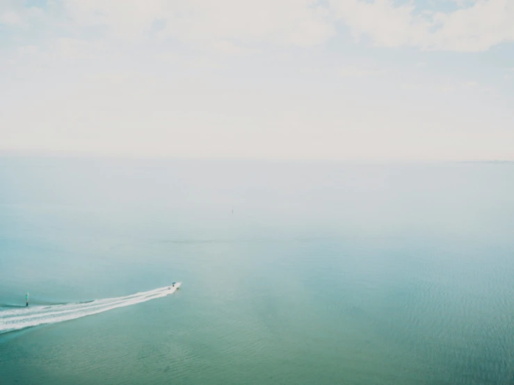 a motor boat and speedboat speeding down a wide ocean