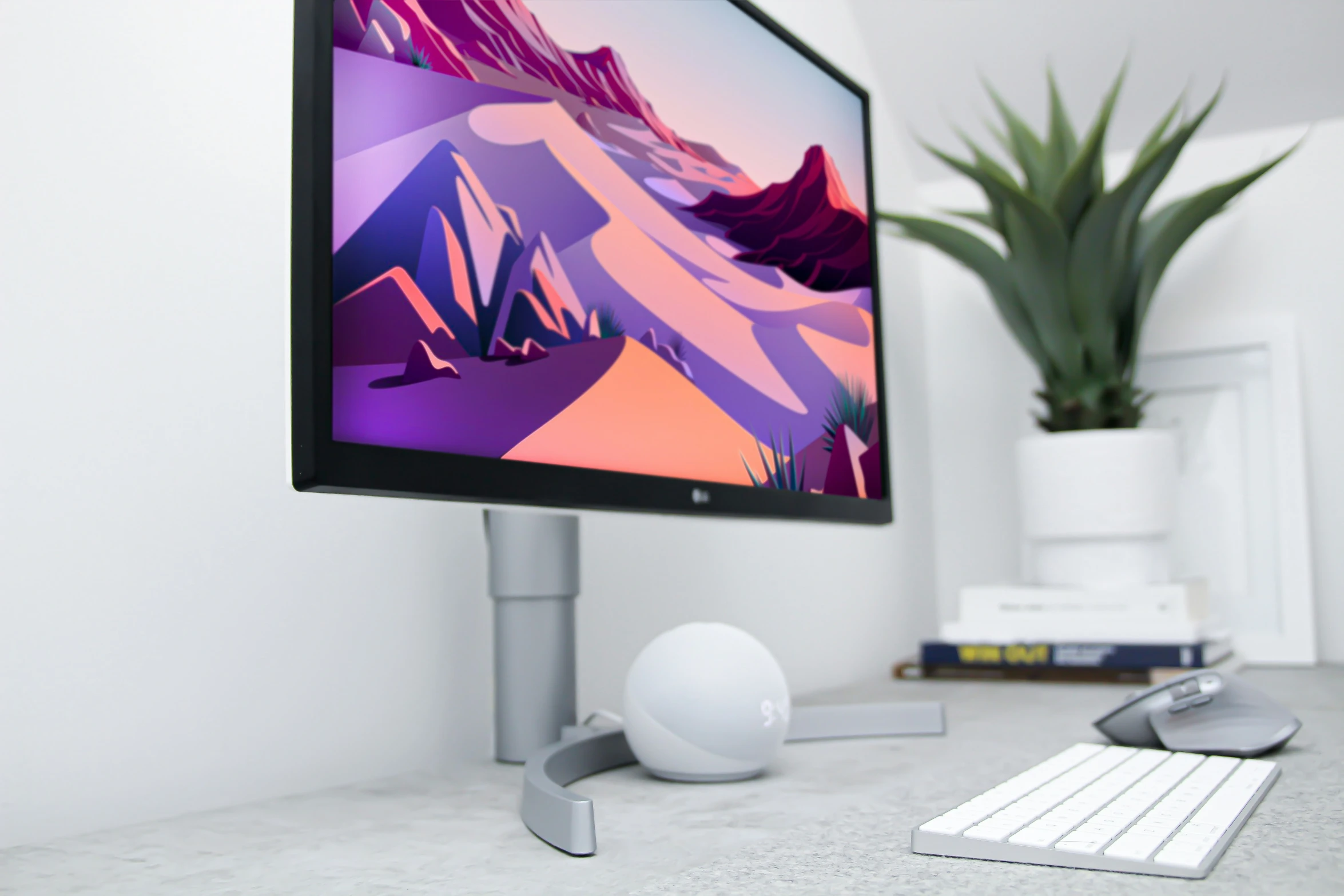 a computer screen with mountains on it and a keyboard, mouse and plant