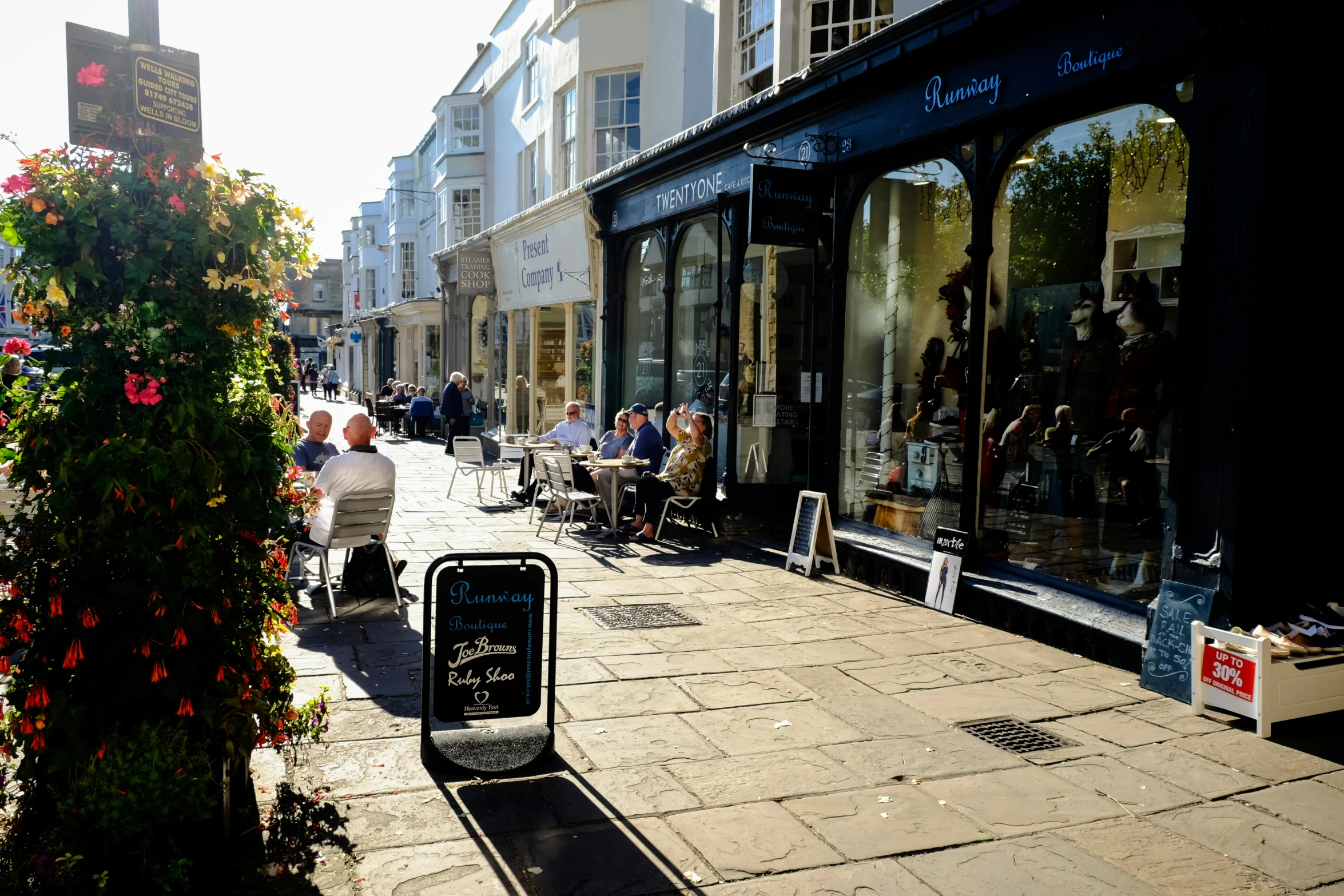 a sidewalk lined with shops, and pedestrians walking down the street